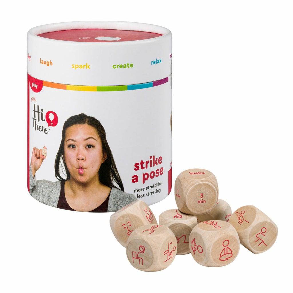 A cylindrical container labeled "strike a pose" with an image of a woman. Next to it are wooden dice, each showing different exercises and durations.