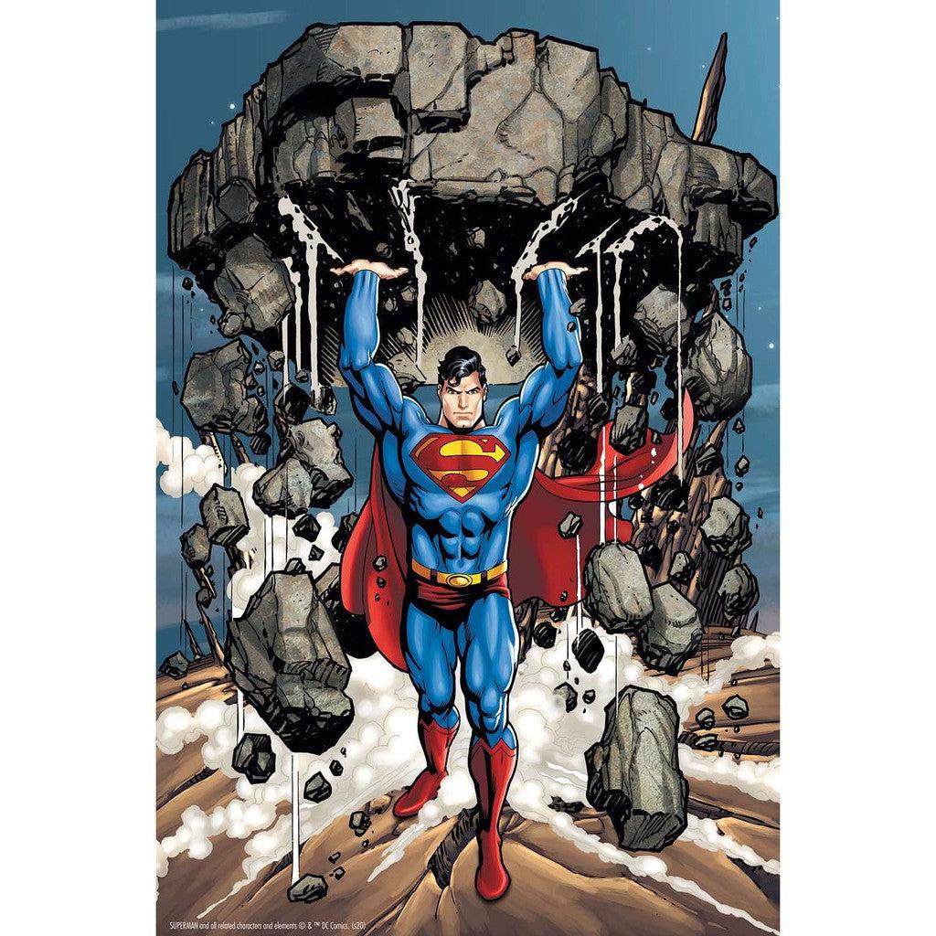 Amidst debris and dust, Superman, the iconic DC Comics superhero in a blue costume and red cape, lifts a massive rock above his head as if it's an oversized toy 