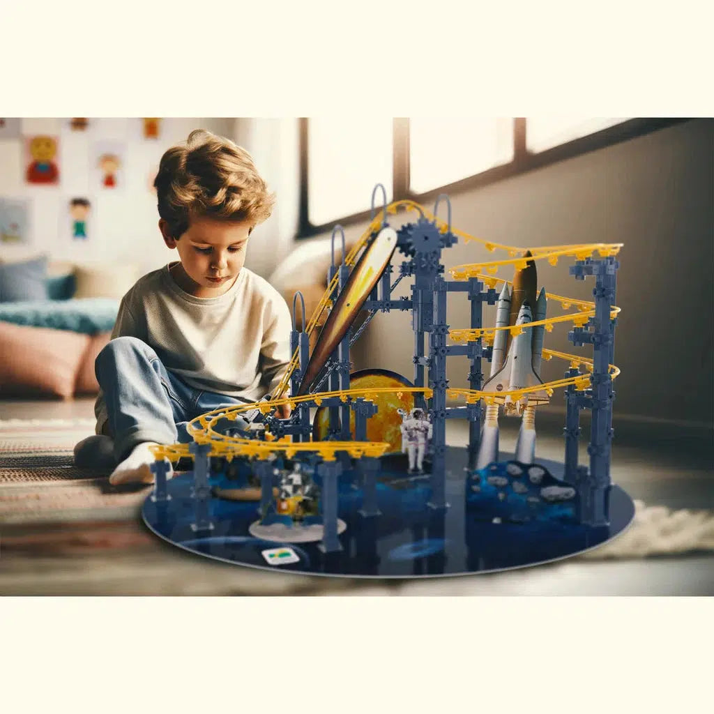 A child sits on the floor, focused on assembling the Techno Trax Galactic Adventure playset with gears, tracks, and a toy rocket. The bright room's soft furnishings complement the sunlight filtering through windows, creating an ideal backdrop for this space-themed roller coaster fantasy.