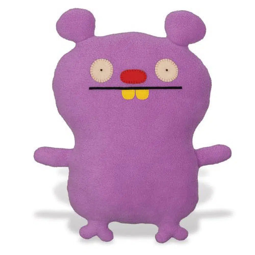 Purple plush toy with two round eyes, a red nose, and yellow teeth stands upright. It has short arms, feet with two toes, and round ears.