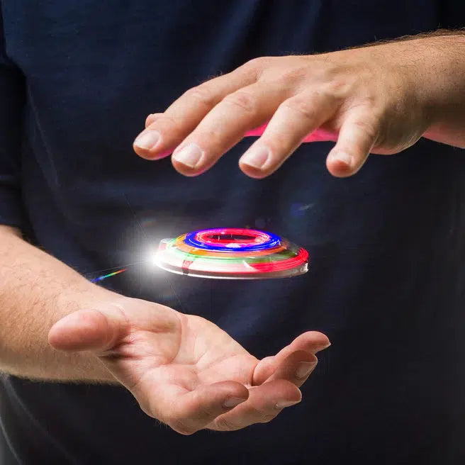 A person holding a colorful, spinning Zorbi Flying Saucer between their hands, mesmerized by its hypnotic light effects.