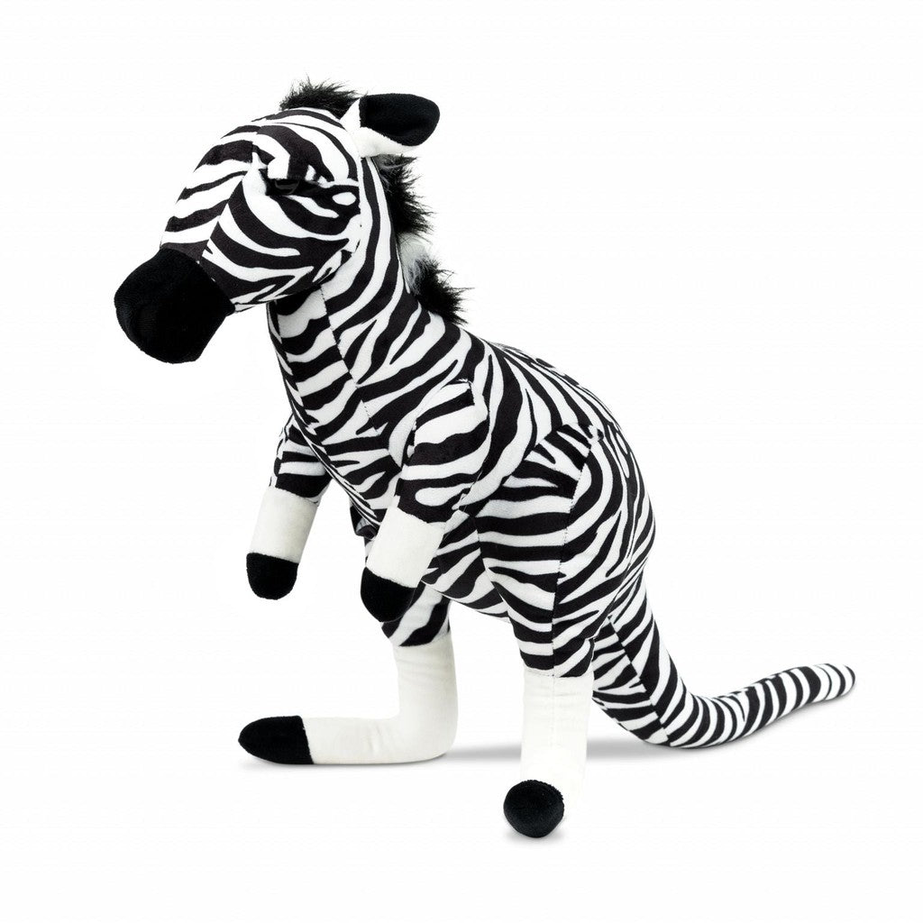 Stuffed zebra toy with black and white stripes, shown standing on its legs with a long tail and a fluffy mane.